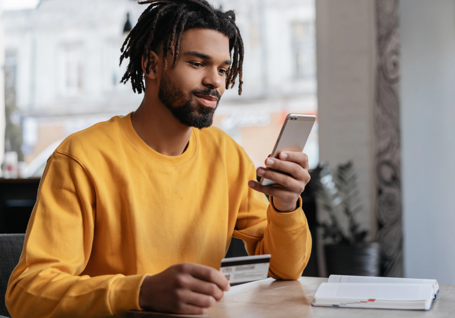 black man in yellow shirt purchase from phone using credit card